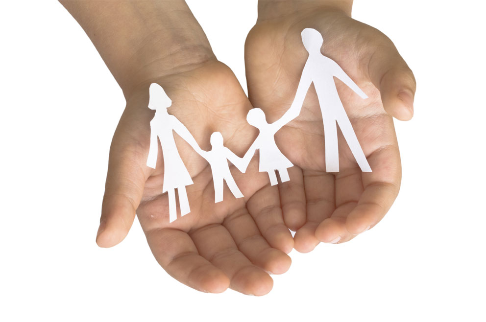 two hands holding a paper cutout of a family